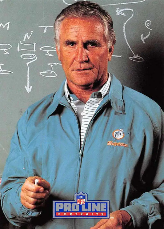 Person in light blue Miami Dolphins jacket in front of chalkboard with Don Shula