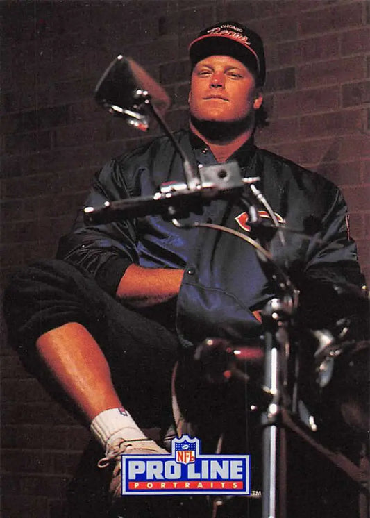 Person in black jacket and cap on motorcycle with Chicago Bears Tom Thayer football card
