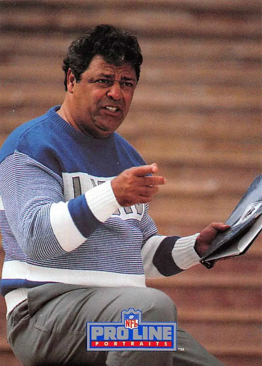 Person in blue and white striped sweater holding documents near Wayne Fontes Detroit Lions football card