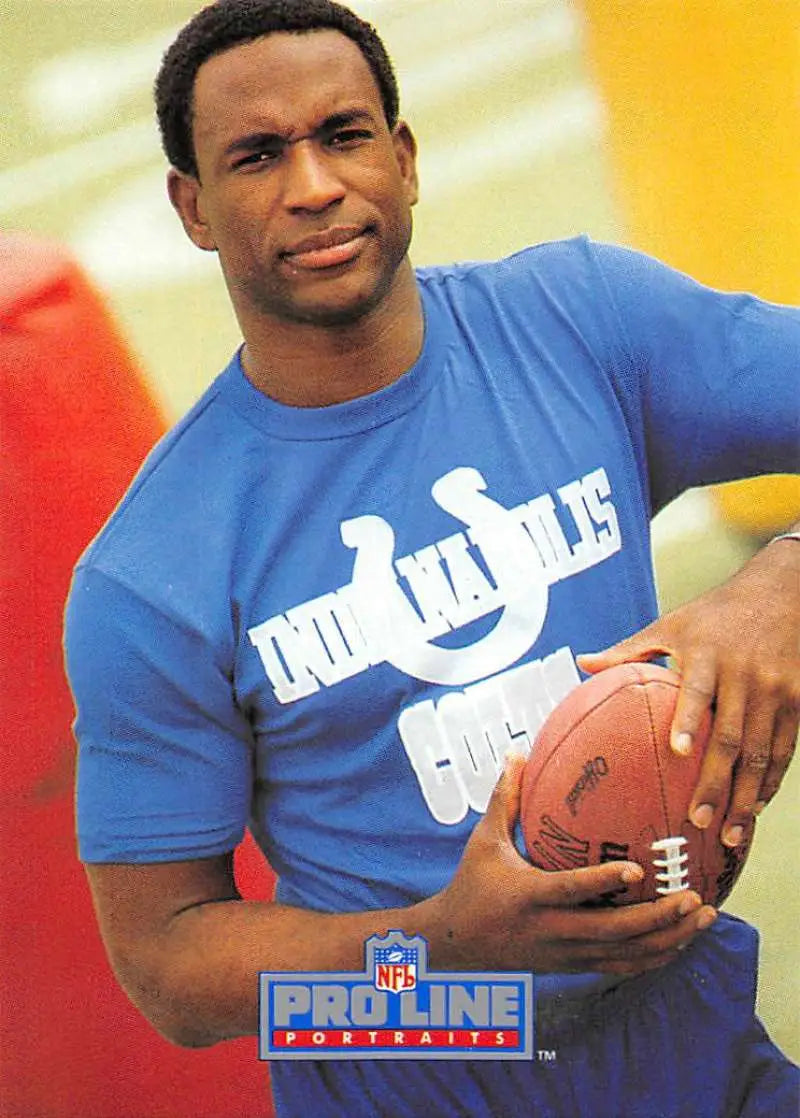 Person in a blue Indianapolis Colts t-shirt holding a football beside Eric Dickerson card