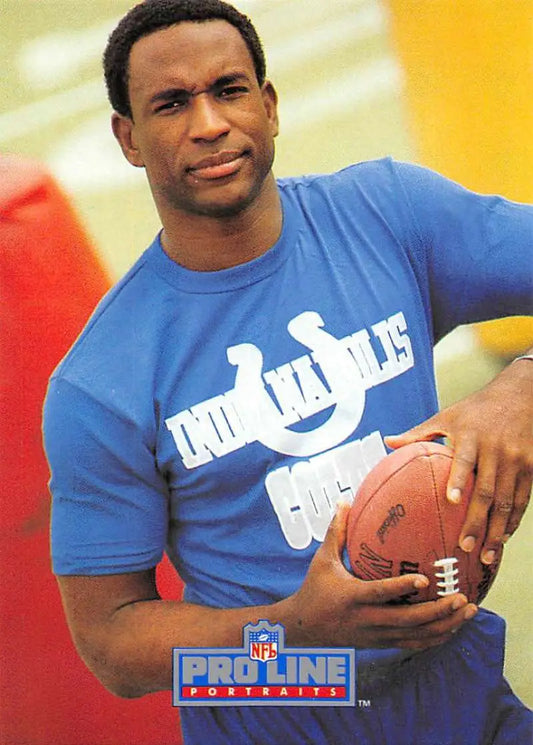 Person in a blue Indianapolis Colts t-shirt holding a football beside Eric Dickerson card