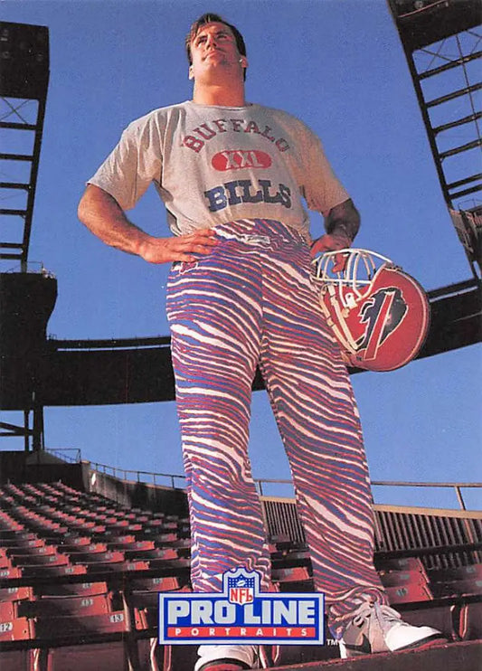 Person in zebra-striped pants and Buffalo Bills t-shirt holding football with Shane Conlan card