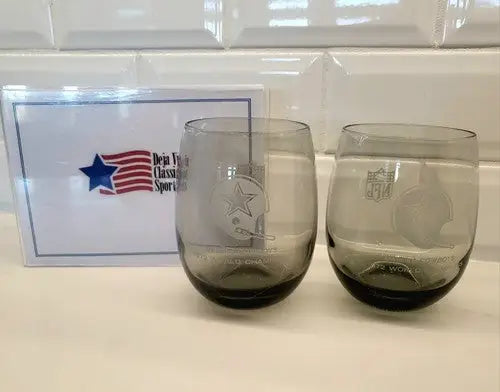 Two smoke gray Dallas Cowboys stemless wine glasses with NFL World Champions logos
