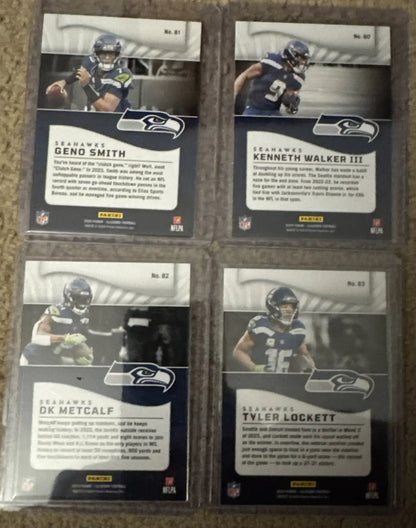 Four Seattle Seahawks trading cards in protective sleeves from 2024 Illusions Emerald Green series