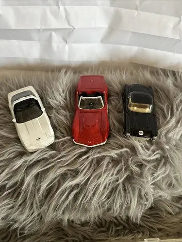 Three colorful diecast cars in a diecast car collection display