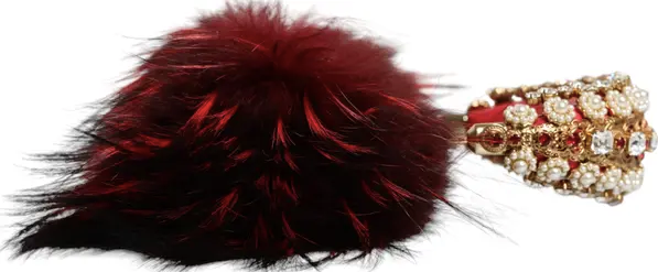 Red feathered item and gold bracelet with gemstones on a white background