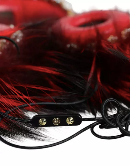 Red feathered product with black strap and gold hardware on a white background