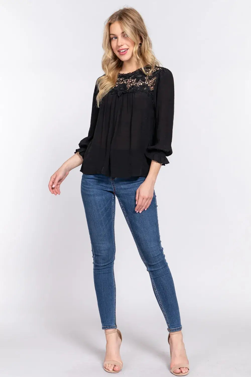 Women’s black crochet lace panel blouse with flounce sleeves, paired with blue skinny jeans