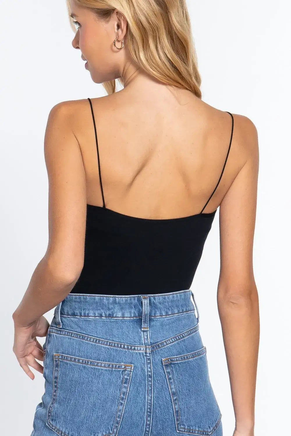 Black ribbed round neck spaghetti strap tank top paired with blue high-waisted denim jeans