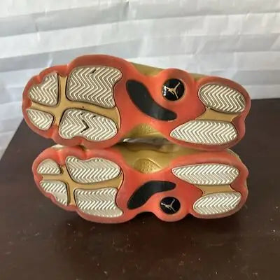 Worn gold and red Air Jordan 13 Retro Chinese New Year sneakers with white patterned soles