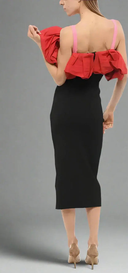 Woman in black Alexander McQueen knitted midi dress with ruffled red cold-shoulder top