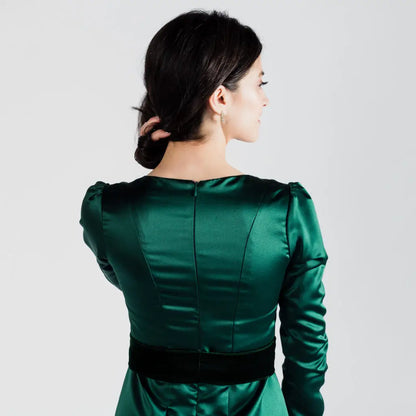 Woman in emerald green poly satin Paris Bloom Noel party dress with black velvet waistband