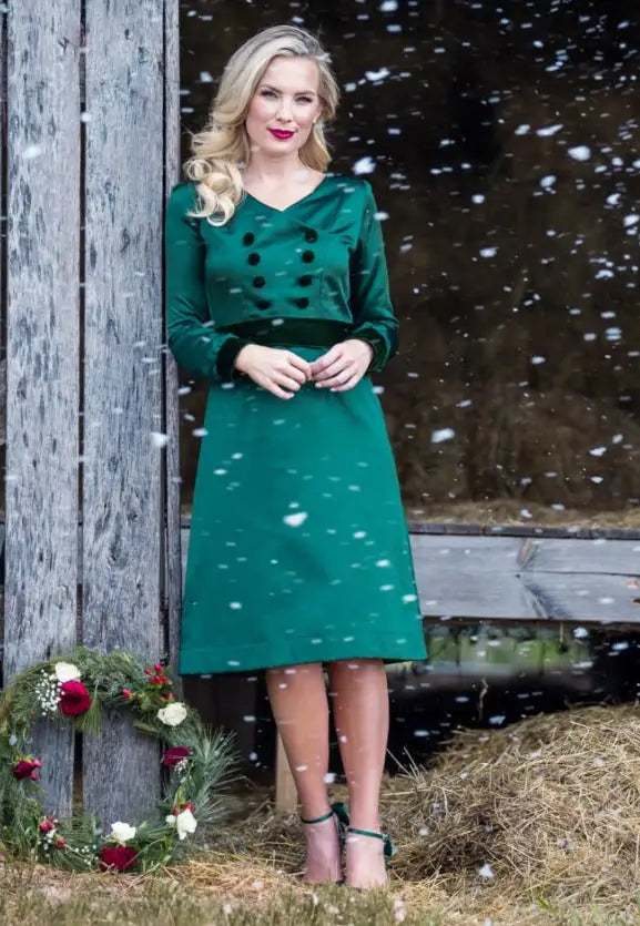 Blonde woman in green poly satin Paris Bloom Noel dress with heels and red lipstick