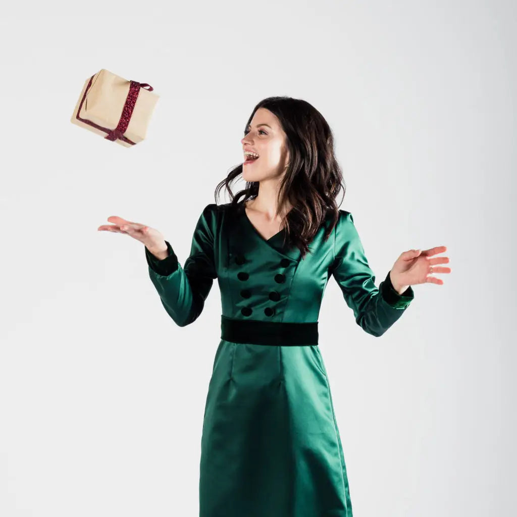 Woman in green poly satin Paris Bloom Noel dress catching a gift for holiday party