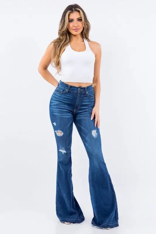 Woman in white halter crop top and distressed dark wash Amber Bell Bottom Jeans
