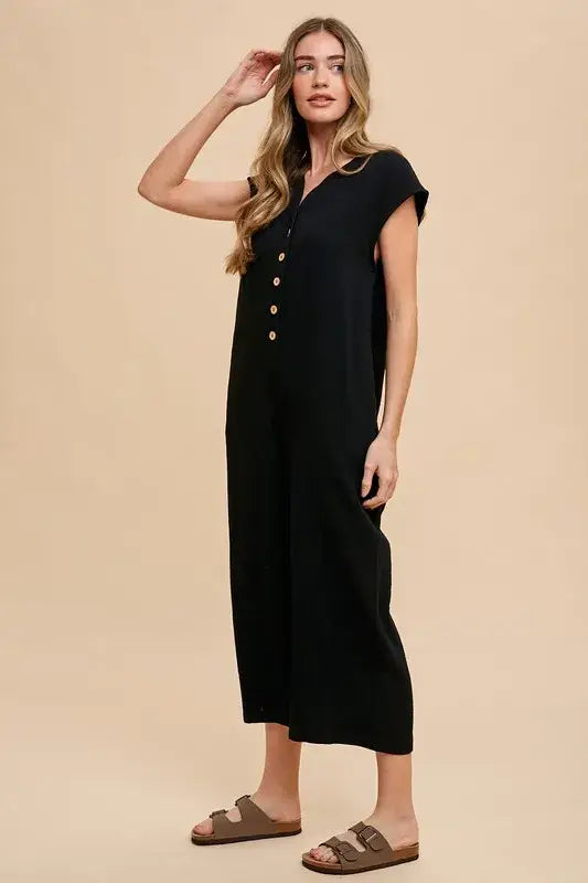 Black linen wide leg jumpsuit with button details, side slits, and cap sleeves