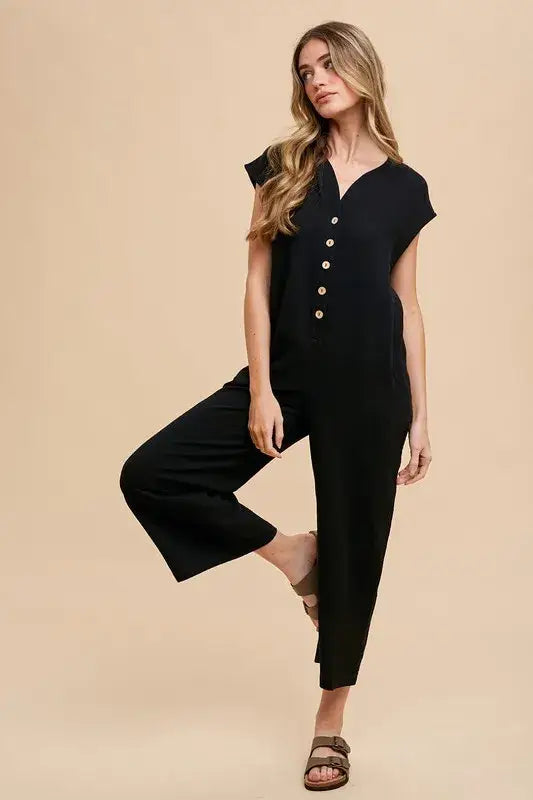 Black wide leg jumpsuit with button front, short sleeves, and stretchy fabric