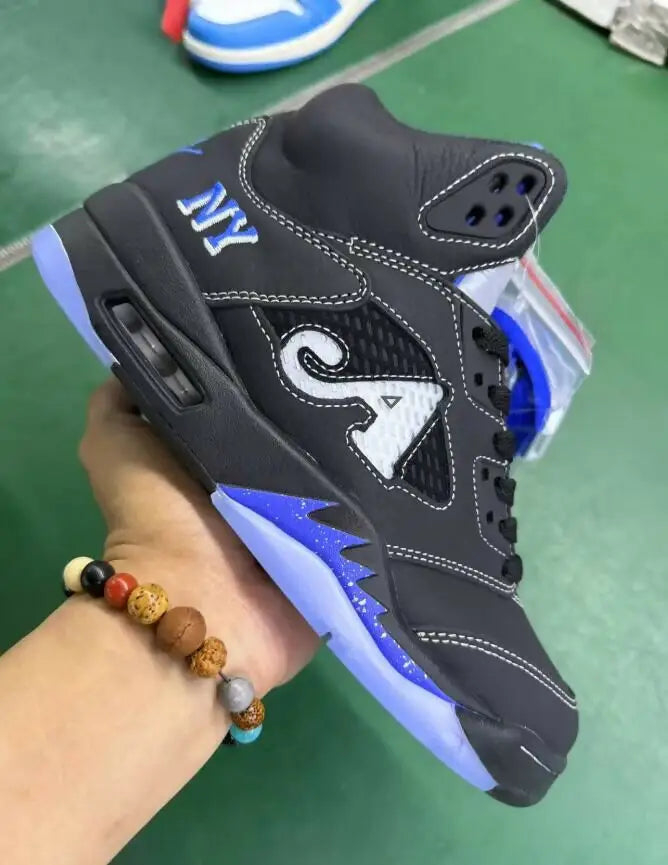 Black high-top sneaker with blue accents and white stitching from Awake Ny x Air Jordan 5 for fast shipping