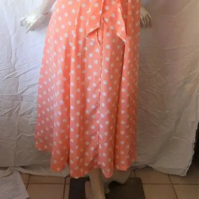 Peach-colored sleeveless dress with white polka dots and tied waist for summer style