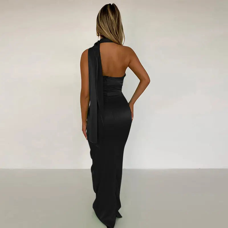 Woman in black satin backless maxi dress with sash detail, perfect for elegant occasions
