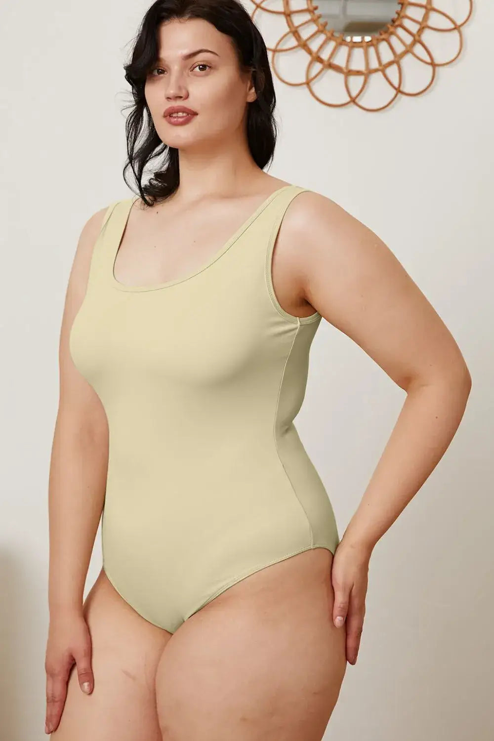 Plus-size woman in beige square neck sleeveless bodysuit, perfect for jeans size selection