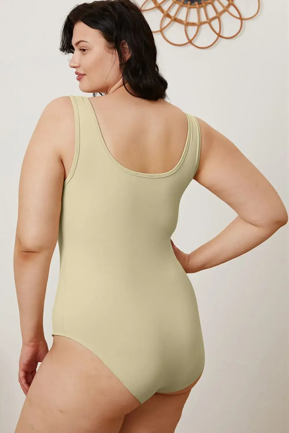 Plus-size woman modeling light-colored square neck sleeveless bodysuit, perfect for jeans size