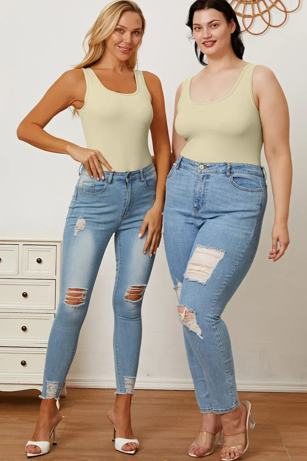 Two women wearing light green tank tops and distressed blue jeans showcasing square neck sleeveless bodysuits