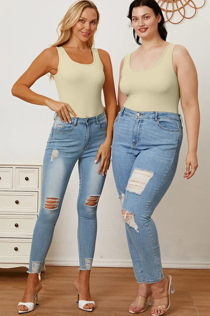 Two women wearing light green tank tops and distressed blue jeans showcasing square neck sleeveless bodysuits