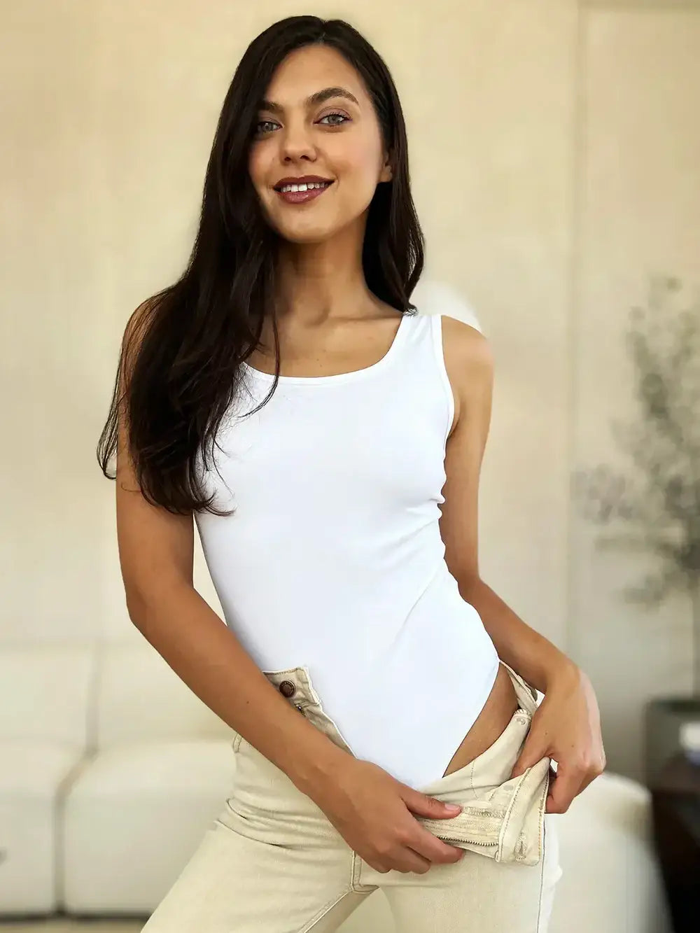 Woman wearing Basic Bae full size square neck sleeveless bodysuit with light-colored jeans