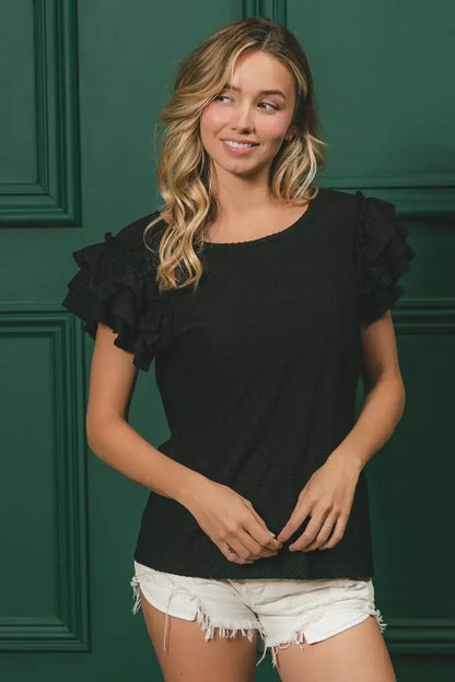 Black ruffled sleeve top with birdseye texture layered design and white denim shorts