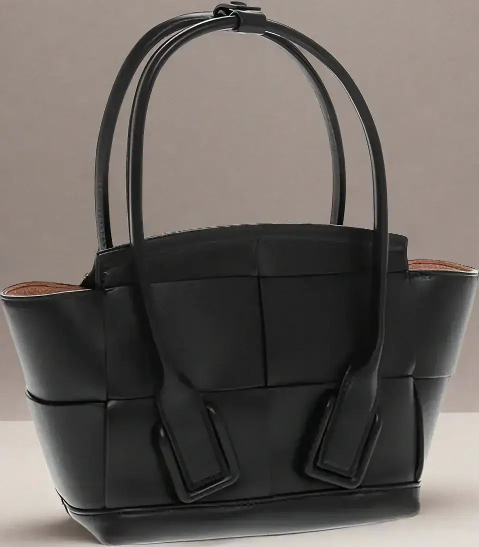 Black leather tote bag with woven design and removable shoulder strap for versatile style