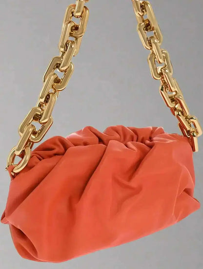 Orange Bottega Veneta chain pouch bag with chunky gold chain strap and magnetic closure