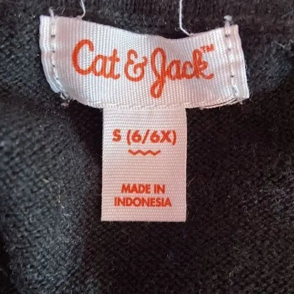 White clothing tag with orange lettering on Cat & Jack Girl’s Black Silver Star Pattern shirt