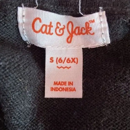 White clothing tag with orange lettering on Cat & Jack Girl’s Black Silver Star Pattern shirt