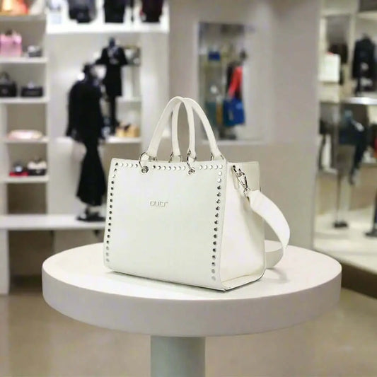White synthetic handbag with studded design, two top handles, and a shoulder strap