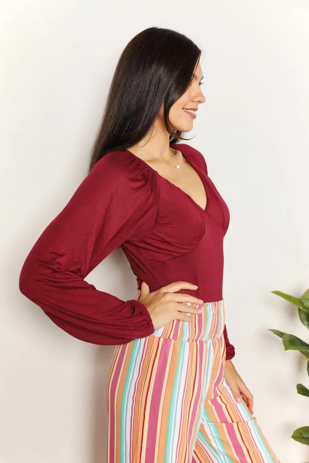 Culture Code full size v-neck bodysuit with poet sleeves and ruffled details paired with colorful striped pants