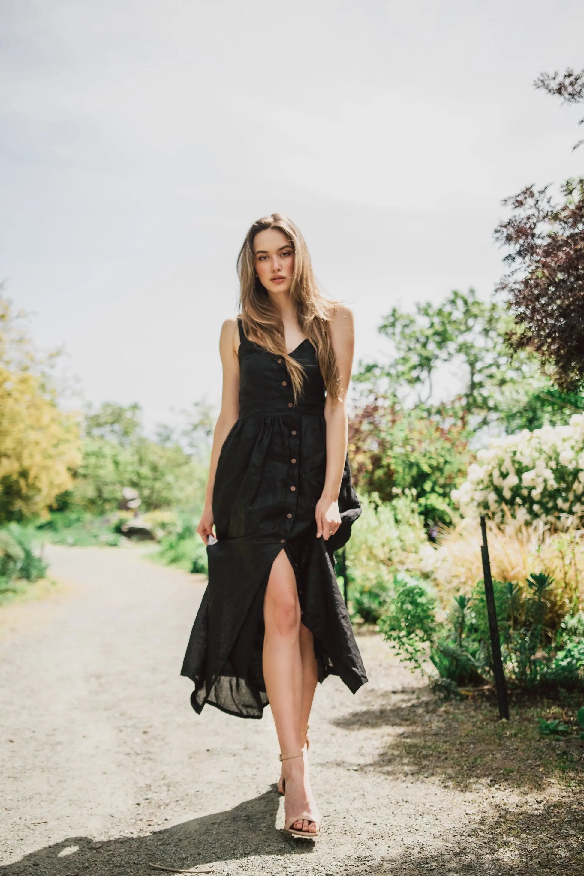 Woman walking in Daria Linen Dress Black with high slit and nude heels during business days