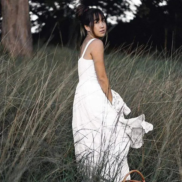 Woman in a white linen dress with thin straps wearing the Daria Linen Dress