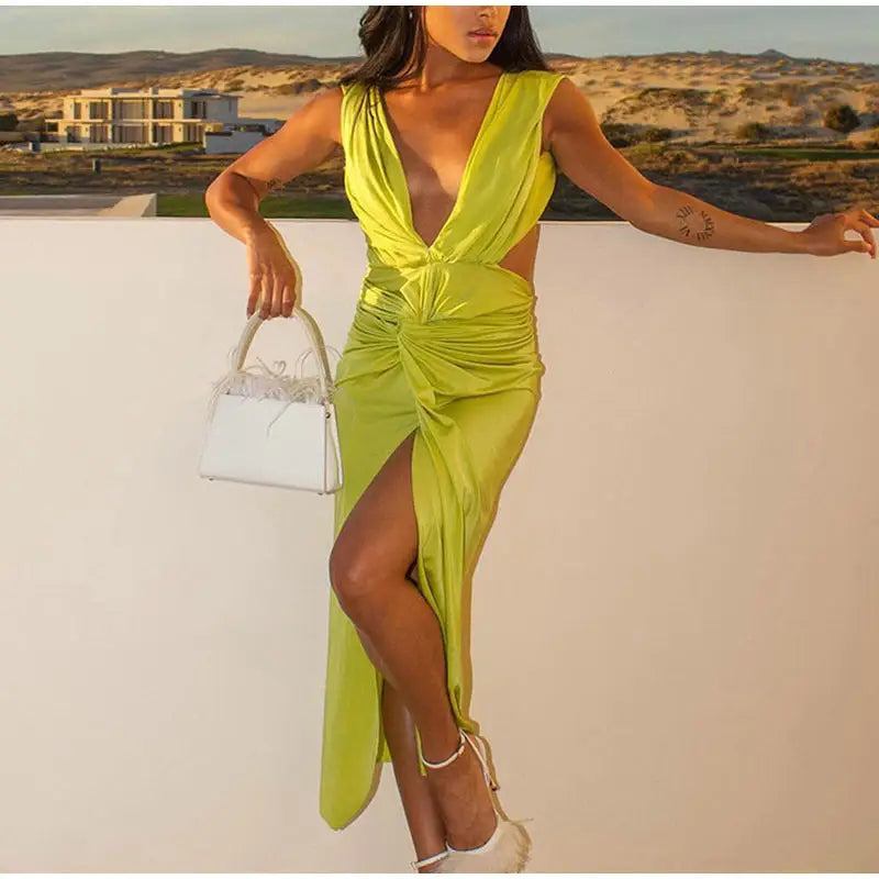 Woman wearing a lime green deep V neck midi dress with side cutouts and high slit