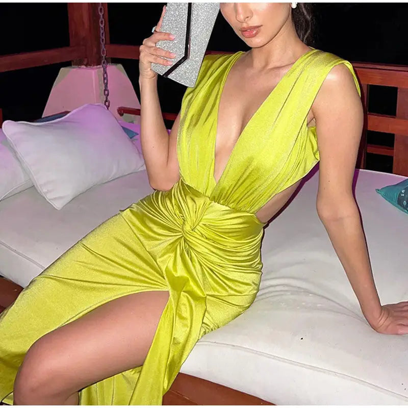 Woman in bright chartreuse green deep V neck midi dress with cutouts and high slit
