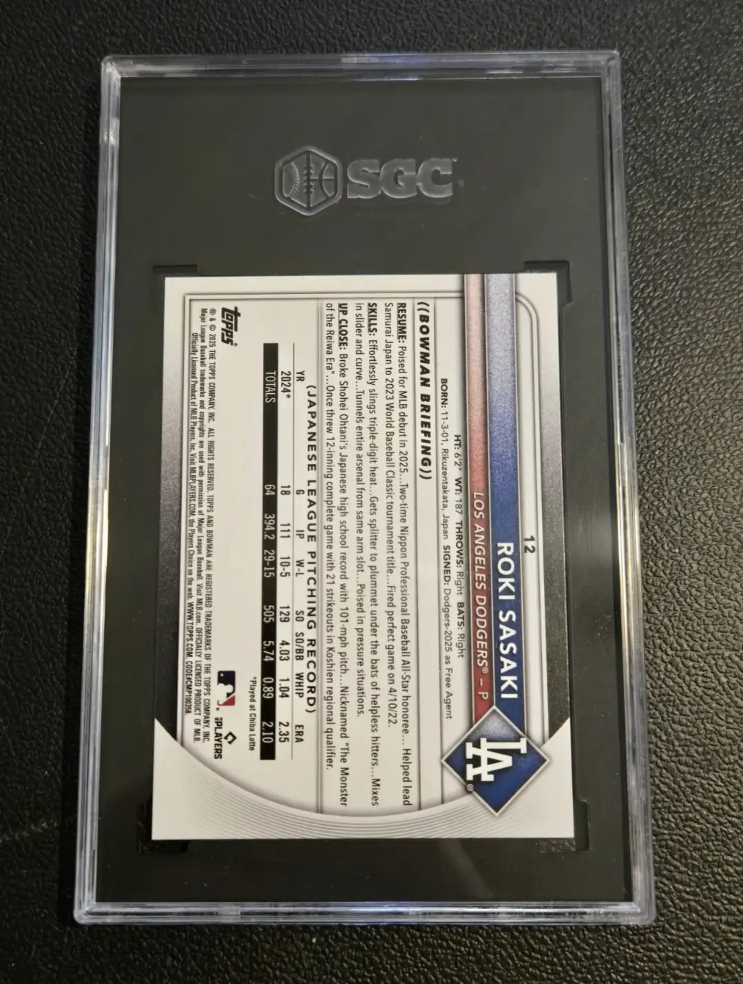 Graded baseball card of Roki Sasaki with Era 9FIFTY Snapback in the Dodgers lot