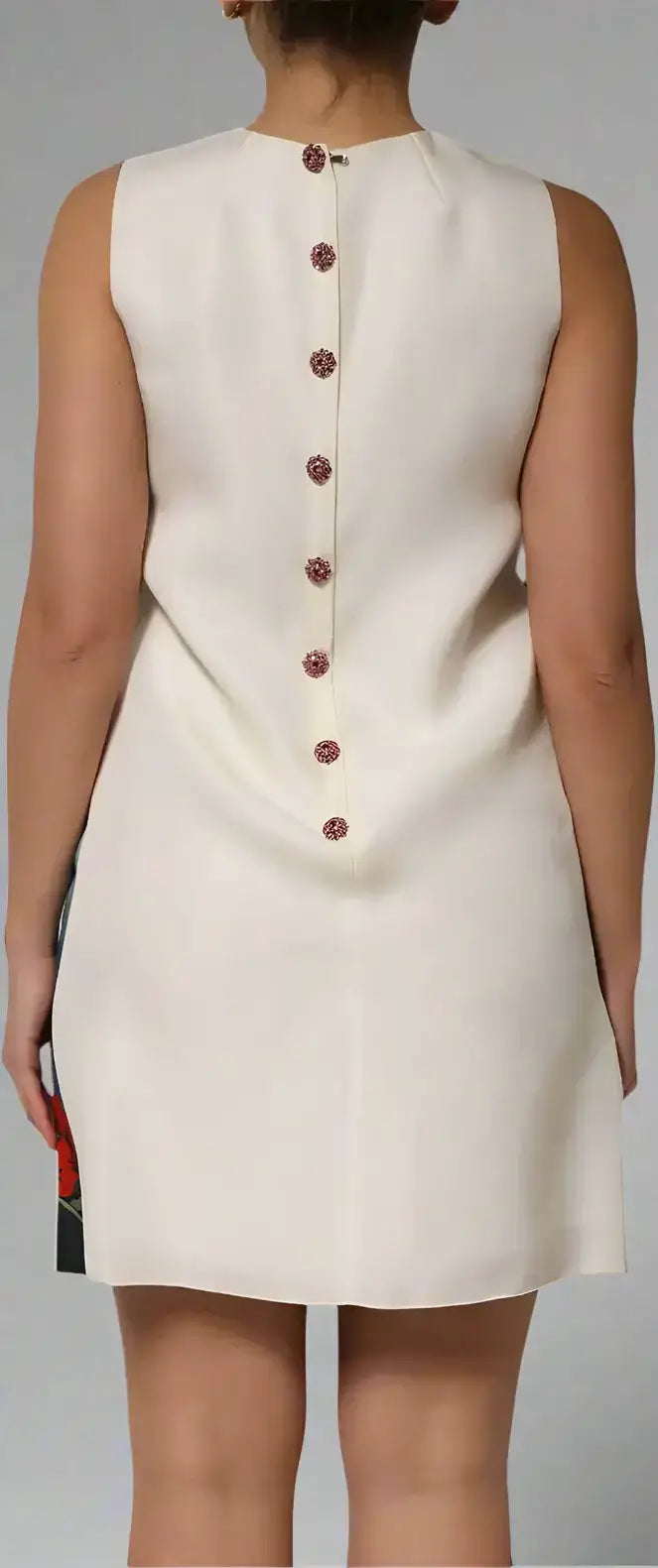 Back view of sleeveless cream mini dress with full-length button placket and decorative buttons