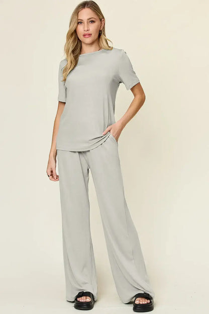 Light gray wide leg pants with black sandals and matching short-sleeved top in wide leg pants set