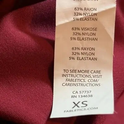 Fabric care tag showing material composition and care instructions for Fabletics Burgundy Short Sleeve Dress with rear zip