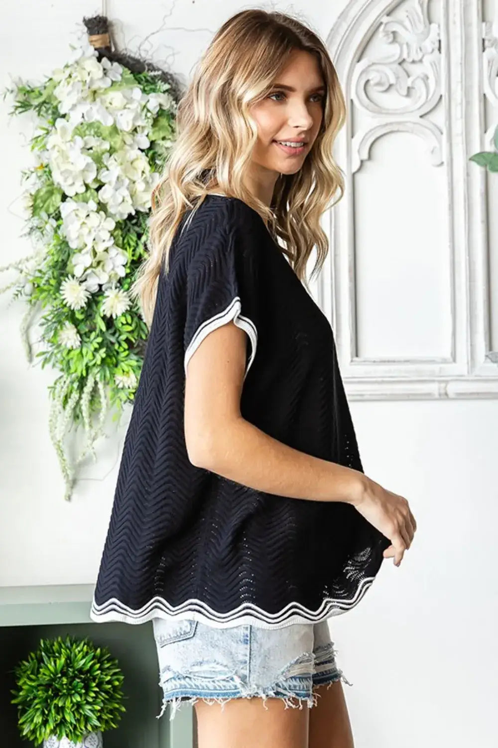 Black textured wavy crochet drop shoulder knit top with white trim and frayed hem