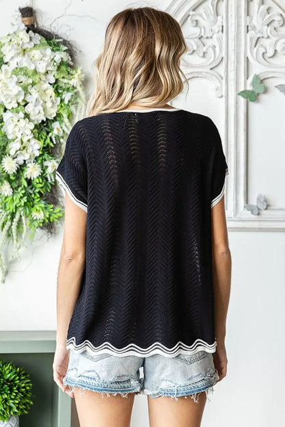 Black textured knit top with white trim and lace hem featuring wavy crochet drop shoulder design