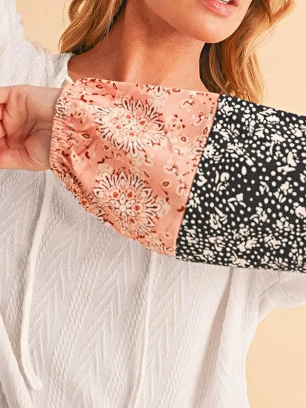 Woman modeling a white floral patchwork long-sleeved top with patterned sleeves