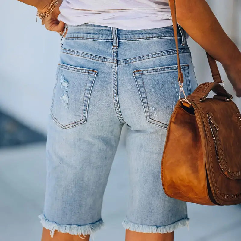Light wash distressed denim shorts with frayed hems, featuring ripped holes and high elasticity
