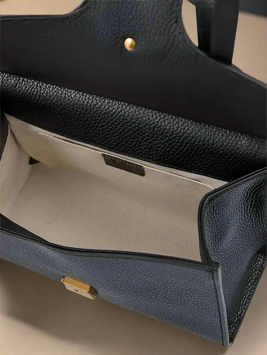 Open black leather GG Marmont handbag with off-white fabric lining and gold clasp