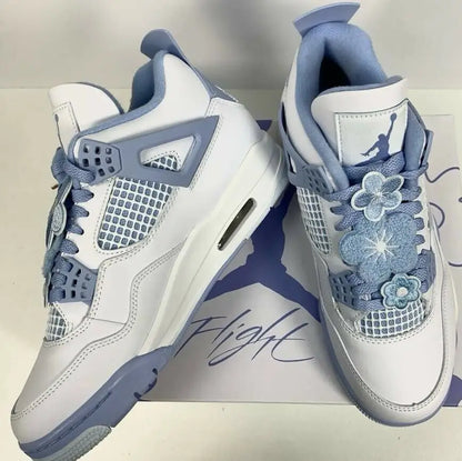 White and light blue Air Jordan 4 sneakers with floral lace embellishments for Jordan 4 Forget Me Not, available with fast shipping within business days depending